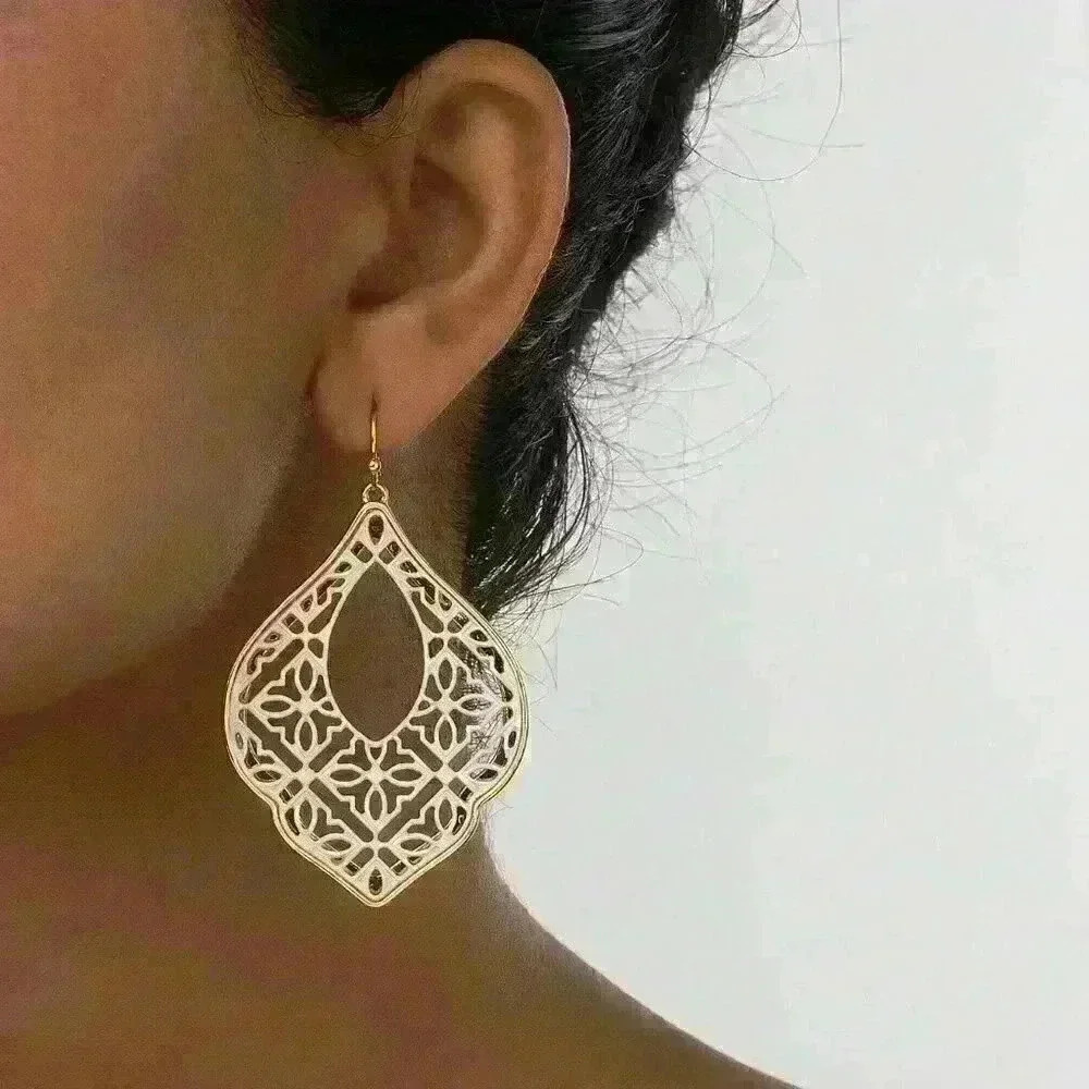 White Filigree Teardrop Statement Earrings framed by elegant gold-tone edges